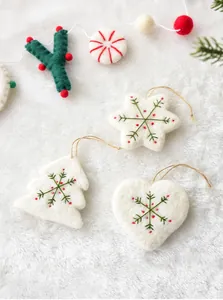 Detailed view of handmade white wool felt snowflake ornaments with red dots and hemp rope