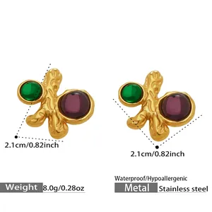 Vue détaillée de boucles d'oreilles dorées en acier inoxydable aux pierres rouge et vert