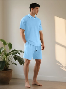 Dettaglio di polo in maglia azzurra da uomo e pantaloncini con coulisse per l'estate