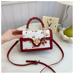 Detail of red and white cherry print handbag with twisted rope handle and floral lock