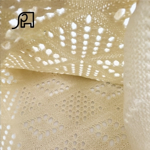 Macro shot of ivory knit fabric showing geometric crochet patterns and fine stitching