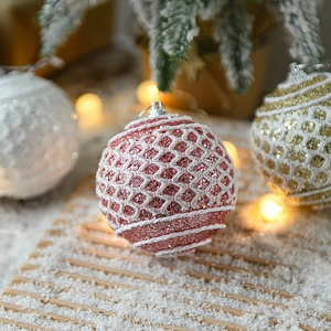 Pink glittery Christmas ornaments with grid texture on snowy background with warm lights