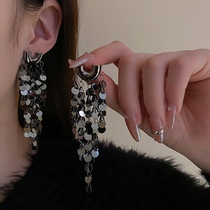 Gros plan de boucles d'oreilles à pompons argentés en forme de U avec des paillettes