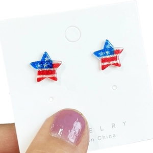 Close-up of sparkling star-shaped earrings with American flag design on a white card