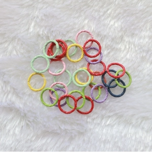 Macro shot of colorful textured jump rings for DIY jewelry making on white faux fur background