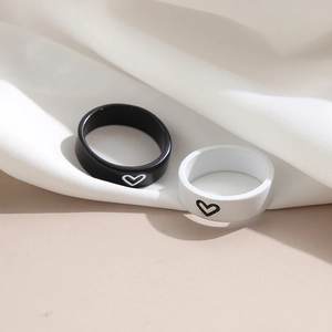 Close-up of black and white matching heart rings on white fabric background