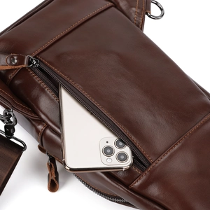 Close-up of premium dark brown leather chest bag featuring smooth zippers and phone pocket