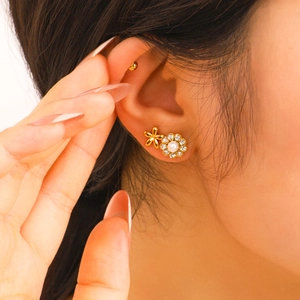 Luxury gold flower earrings with white pearls and sparkling zircons on model