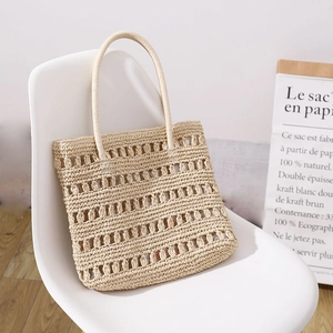 Minimalist beige hollow woven straw handbag on a white chair for summer beach vacations
