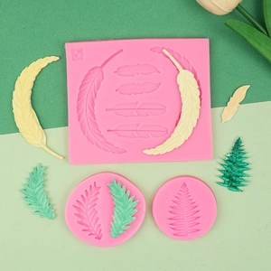 Détail du moule en silicone rose pour plumes et feuilles avec des modèles finis en résine