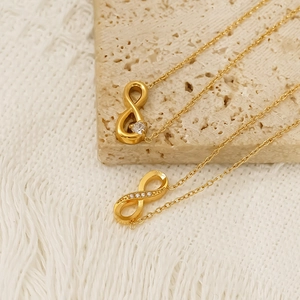 Elegant gold infinity symbol necklaces with white cubic zirconia on textured stone
