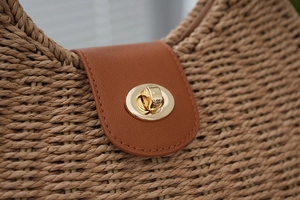 Close-up of retro woven beach bag featuring a brown leather lid and golden metal twist lock