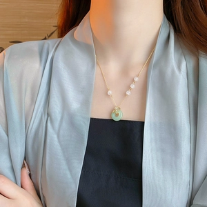 Gros plan du collier ginkgo plaqué or avec pendentif en jade vert sur le cou