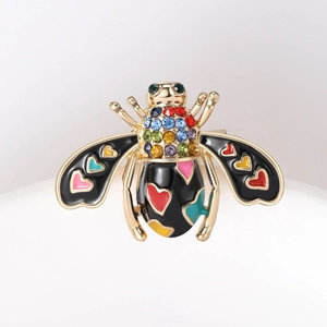 Close-up of golden honey bee brooch with colorful enamel hearts and crystal rhinestones