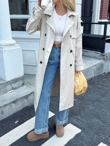 Scatto street style di un trench beige a doppio petto con spalline classiche e cintura in vita