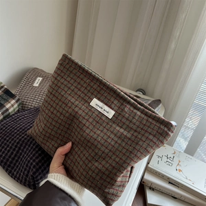 Close-up of vintage plaid wool makeup bag with simple wish label and soft texture