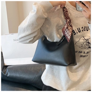 Mirror selfie showing a black matte shoulder bag with a silk scarf wrapped around the handle