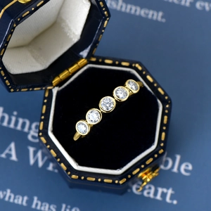 Macro shot of gold five-stone moissanite ring in a premium blue velvet jewelry box