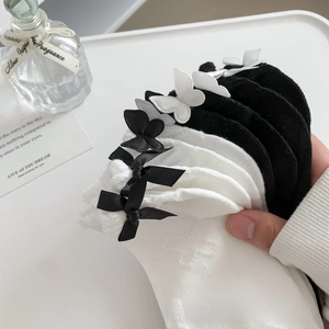 Detail of white cotton socks with black bow accents and delicate butterfly embroidery