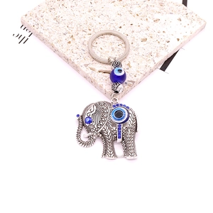 Tribal elephant keychain in vintage silver with blue evil eye beads on stone background