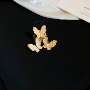 Macro shot of three golden butterflies brooch with white enamel and sparkling zircons
