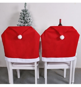 Detailed view of two red velvet Christmas hat chair covers in a festive holiday setting