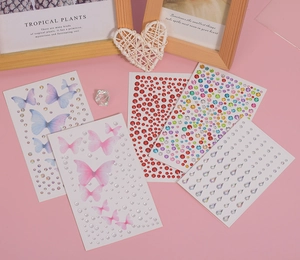 Flat lay of five assorted face gem stickers featuring butterfly and rhinestone designs