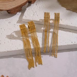 Elegant gold and bicolor tassel drop earrings with metal bead chains on stone display