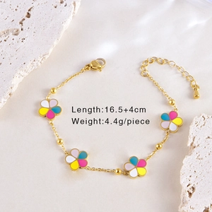 Détail d'un bracelet doré avec fleurs colorées en émail sur fond de pierre texturée