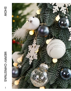 Close-up of mini PE Christmas tree with white ornaments, bird feathers, and LED lights