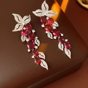 Détail de boucles d'oreilles feuilles en argent avec pierres rouges et cristaux sur cuir