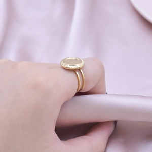 Detail of golden stainless steel double-band ring with engraved circular top on silk