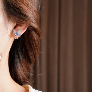 Detailed close-up of zircon butterfly ear clip in 18k gold plating on model's ear