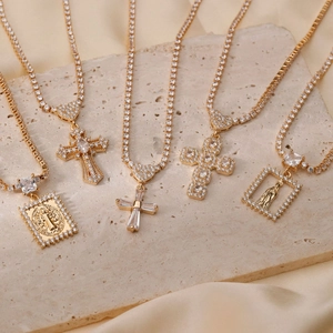 Elegant gold religious necklaces with cross and icon pendants on textured stone background