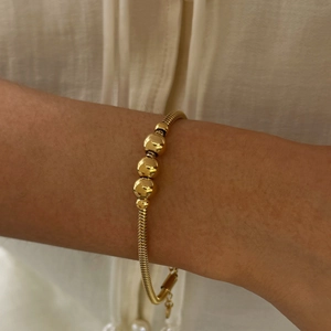 Close-up of golden stainless steel bead bracelet with snake chain worn on wrist