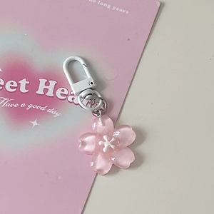 Macro shot of translucent pink resin cherry blossom pendant with a white snap hook clasp