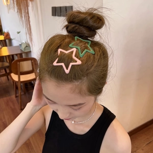 Macro shot of colorful star-shaped metal hair clips on a bun for Y2K style styling