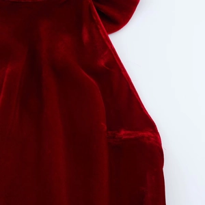 Détail de la robe en velours rouge montrant la texture du tissu et la finition des coutures