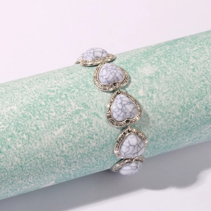 Detailed macro view of retro heart-shaped links with white turquoise stones and silver finish