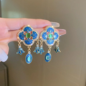 Macro shot of vintage court-style earrings with blue enamel and green gemstone details