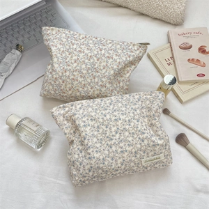 Set di borse per cosmetici in velluto a coste floreale su biancheria da letto bianca