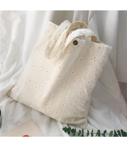 Detail of daisy embroidery on beige canvas tote bag with a vintage bronze snap button