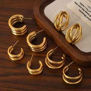 Minimalist gold tiered hoop earrings with layered circular design on wooden tray