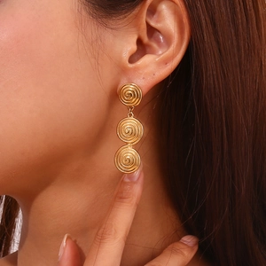Gros plan de boucles d'oreilles spirales dorées géométriques avec texture martelée