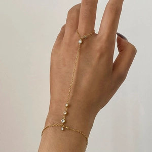 Detail of a gold-plated finger bracelet featuring sparkling white zircon stones on a hand