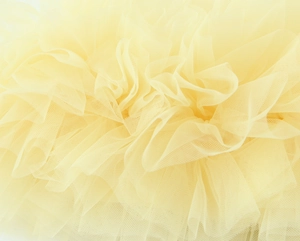 Dettaglio di strati in rete plissettata giallo crema con delicata trama in tulle