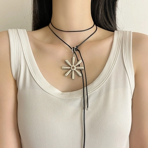 Macro shot of an eight-petal silver flower pendant on an adjustable black double cord