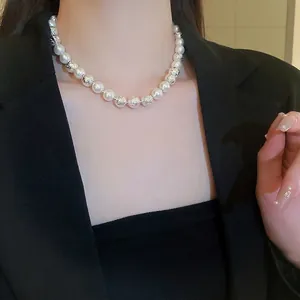 Elegant faux pearl necklace with silver metallic beads on model in black suit