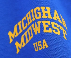 Détail de l'imprimé jaune Michigan sur le tissu en coton bleu délavé du t-shirt