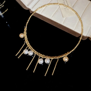 Detail of vintage gold pearl tassel choker featuring twisted rope texture on black background